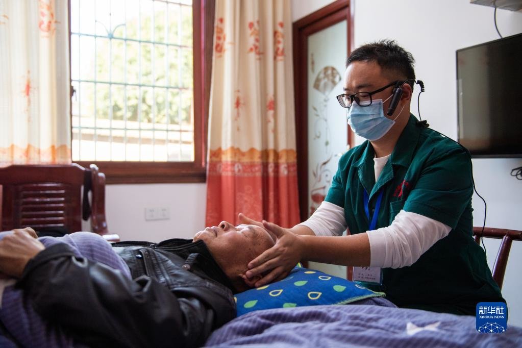 2021年11月12日,在湖南省长沙市长沙县果园镇田汉社区,医务人员彭永(右)为居家老人做头部推拿。新华社记者 陈思汗 摄